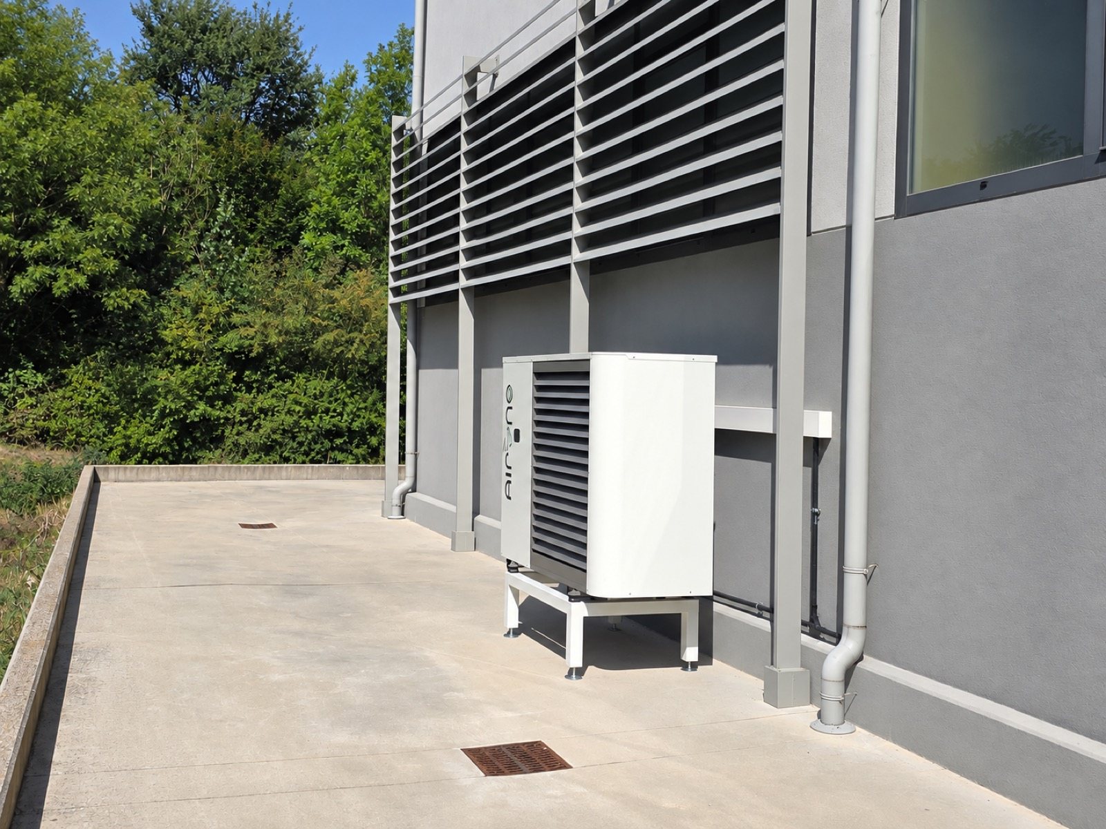 Installazione reale di una unità esterna AirONE collocata a terra lungo il perimetro di un edificio produttivo